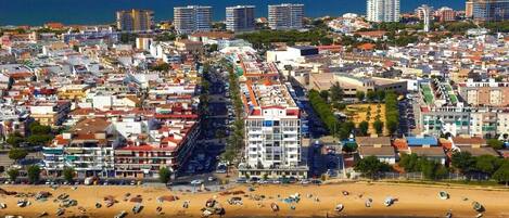 Un paisaje urbano costero con playa, edificios y barcos.