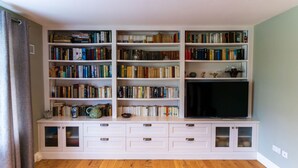 Une pièce comprenant une bibliothèque, un téléviseur et un meuble avec des tiroirs.