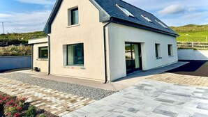 A modern single-story house with a sloped roof, large windows, and a paved driveway. - The Summit - Skellig Coast (Cahersiveen)