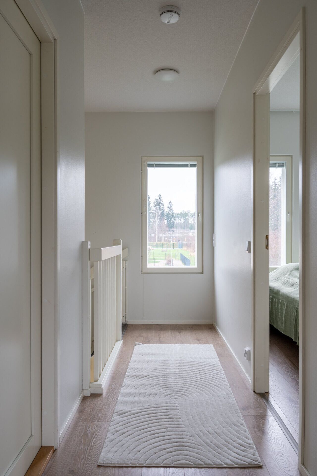 Een kamer met een groot raam, een witte deur en een witte vloer.