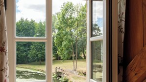 Una habitación con un amplio ventanal corredero que da a un área exterior con un estanque y árboles.