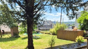 A residential backyard with a tree, a small garden bed, and a wooden fence.
