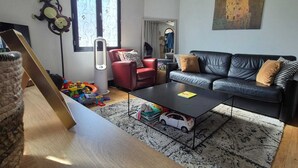 A living room with a sofa, a coffee table, and a window with curtains.