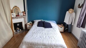 A bedroom with a bed, a dresser, a mirror, a fireplace, and a mannequin.