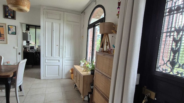 A room with a dining table, chairs, a cabinet, a hanging light fixture, and a door with a window.