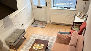 A room with a sofa, a small table with a board game, a bench, a radiator, and a window with a view. - Hidden Gem Townhouse - Cahersiveen (Cahersiveen)