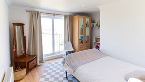 A bedroom with a bed, a dresser, a mirror, a chair, and a window with curtains. - Hidden Gem Townhouse - Cahersiveen (Cahersiveen)