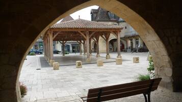 Une arche mène à une cour intérieure agrémentée d’un pavillon en bois, de bancs et de bornes en pierre.
