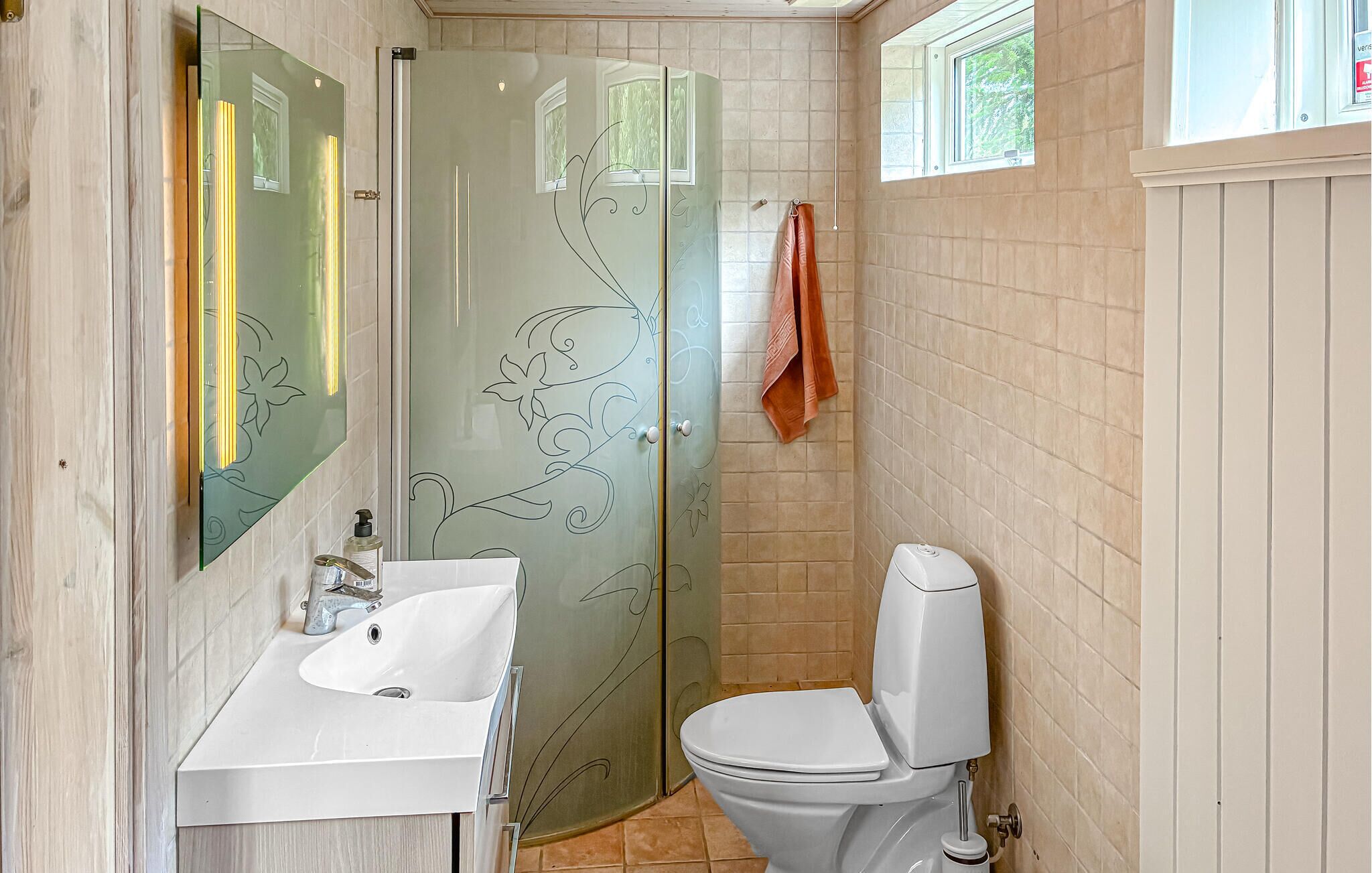 A bathroom with a glass shower door, a white sink, and a toilet.