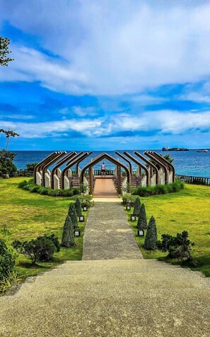 A pathway leading to a wooden structure with a view of the sea.