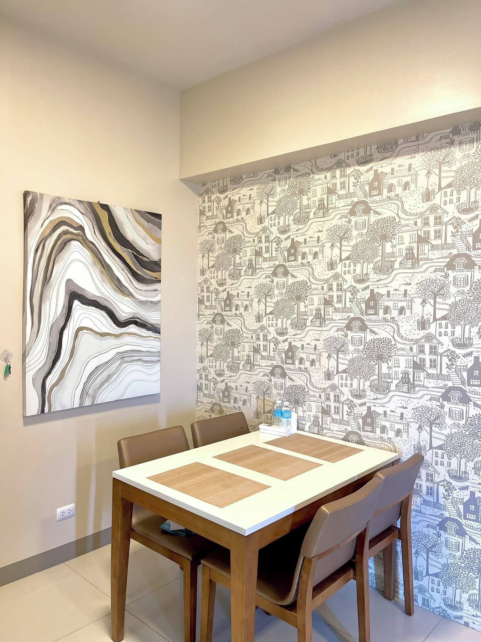 A dining area with a table, chairs, and a wall with a patterned wallpaper.