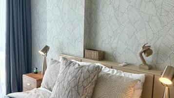 A modern bedroom with a large bed, two bedside tables, a nightstand, a lamp, and a decorative wall panel.