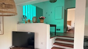 Un salon avec un téléviseur, une table basse en bois et un escalier menant à une autre pièce.