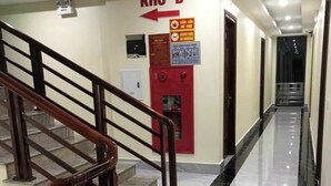 A hallway with a staircase, a fire extinguisher, and a directional sign.