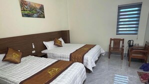 A hotel room with two beds, a wooden headboard, a painting on the wall, a window with blinds, and a wooden chair.