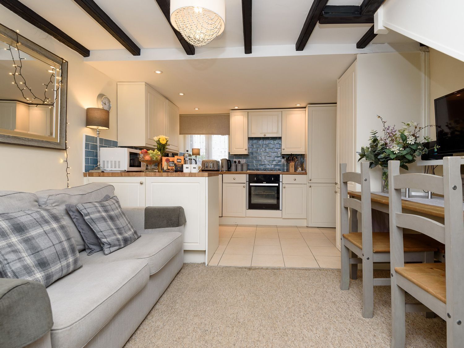 A modern kitchen with white cabinets, a built-in oven, and a dining area with a wooden table and chairs.