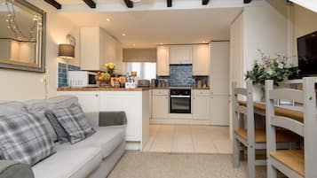 A modern kitchen with white cabinets, a built-in oven, and a dining area with a wooden table and chairs.