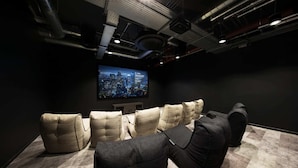 A home theater room with a large flat-screen TV, multiple cushioned seating, and exposed ductwork on the ceiling. - Student Only White Rose View (Leeds)