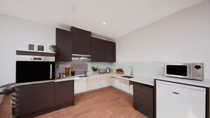 A modern kitchen with dark cabinets, a built-in oven, a microwave, and a dishwasher. - Student Only White Rose View (Leeds)