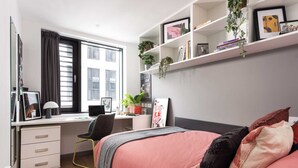 A bedroom with a bed, a desk, a chair, a bookshelf, and a window. - Student Only White Rose View (Leeds)