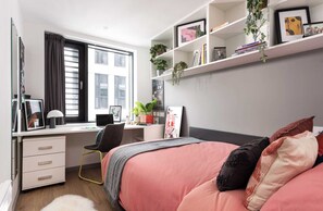 A bedroom with a bed, a desk, a chair, a bookshelf, and a window. - Student Only White Rose View (Leeds)