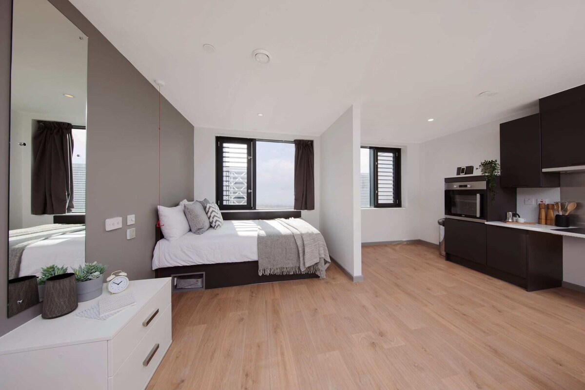 A modern bedroom with a bed, bedside table, and a large mirror.