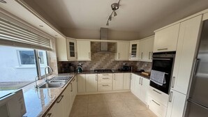 A modern kitchen with white cabinets, a stainless steel refrigerator, and a built-in oven. - Carhan River  Holiday Home - Cahersiveen (Cahersiveen)