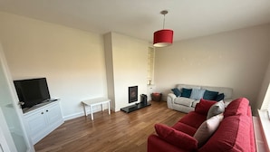 A living room with a red sofa, a white couch, a television, and a red pendant light. - Carhan River  Holiday Home - Cahersiveen (Cahersiveen)