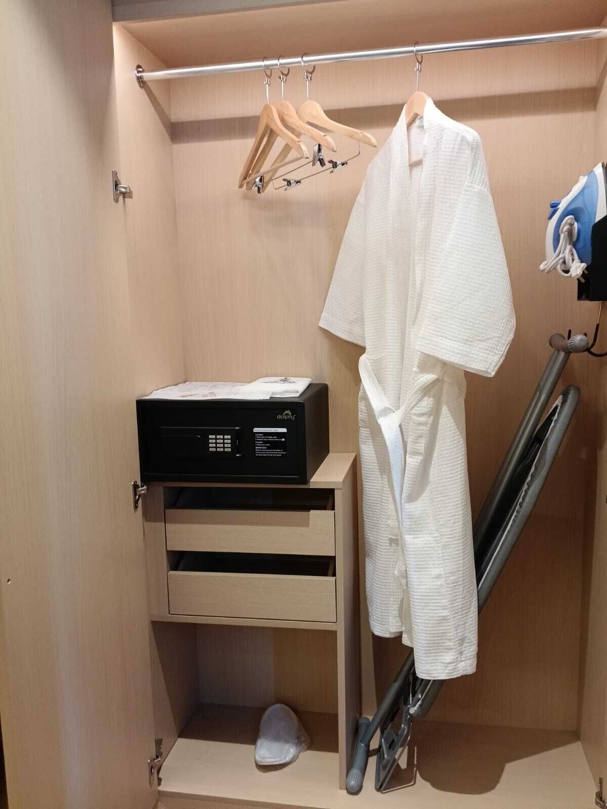 A walk-in closet with a hanging rack, a shoe rack, and a black electronic device on a shelf.