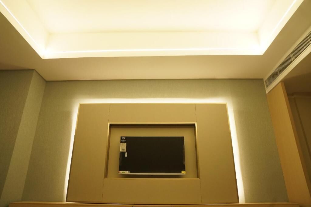 Techo con iluminación empotrada, un cuadro enmarcado y una rejilla de ventilación en la pared.