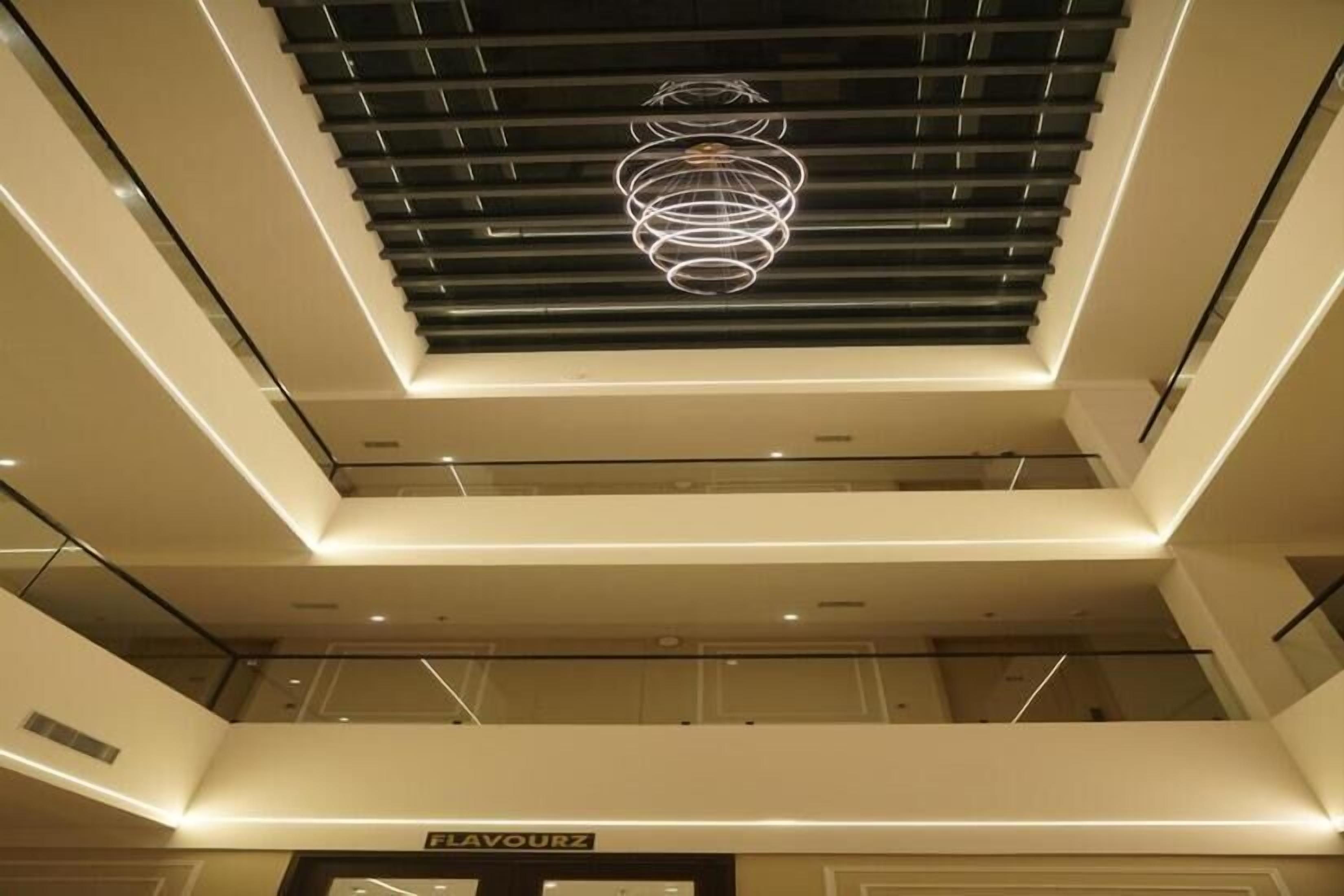 A multi-level interior with a modern ceiling design, a visible store named 'FLAVOURZ,' and a glass railing on the upper level.