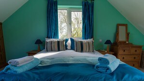 A bedroom with a bed, two bedside tables, a dresser, and a window with curtains. - An Charraig - Killarney (Killarney)