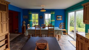 A dining area with a table set for four, a wooden cabinet, and a view through a glass door. - An Charraig - Killarney (Killarney)