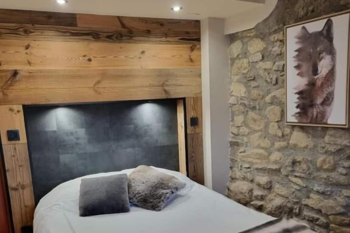 Un dormitorio con una cama, una pared de piedra y un cuadro enmarcado de un lobo.