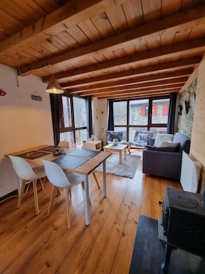 Una habitación con piso de madera, una mesa de comedor, sillas, un sofá y una chimenea.