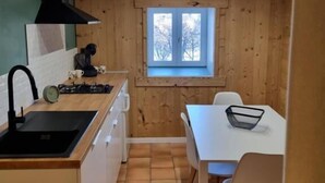 Cocina pequeña con ventana, un lavamanos y zona de comedor con sillas.