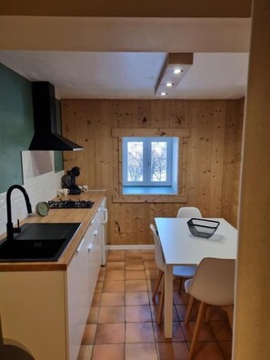 A compact kitchen with a window, a sink, and a dining area with chairs.