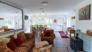 A spacious living room with a large mirror, patterned sofas, a wooden coffee table, a fireplace, and a dining area with a wooden table and chairs. - Valentia central,  high spec bungalow wifi &views (Reenglass)