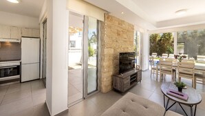 A modern kitchen with a built-in oven and a dining area with a stone fireplace. - Milos lifestyle villas H9- 4 bedroom villa with private pool (Paralimni)