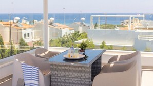A balcony with a table, chairs, and a view of the sea. - Milos lifestyle villas H9- 4 bedroom villa with private pool (Paralimni)