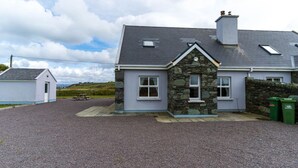 Une maison avec une façade en pierre, un toit gris et une allée gravillonnée.