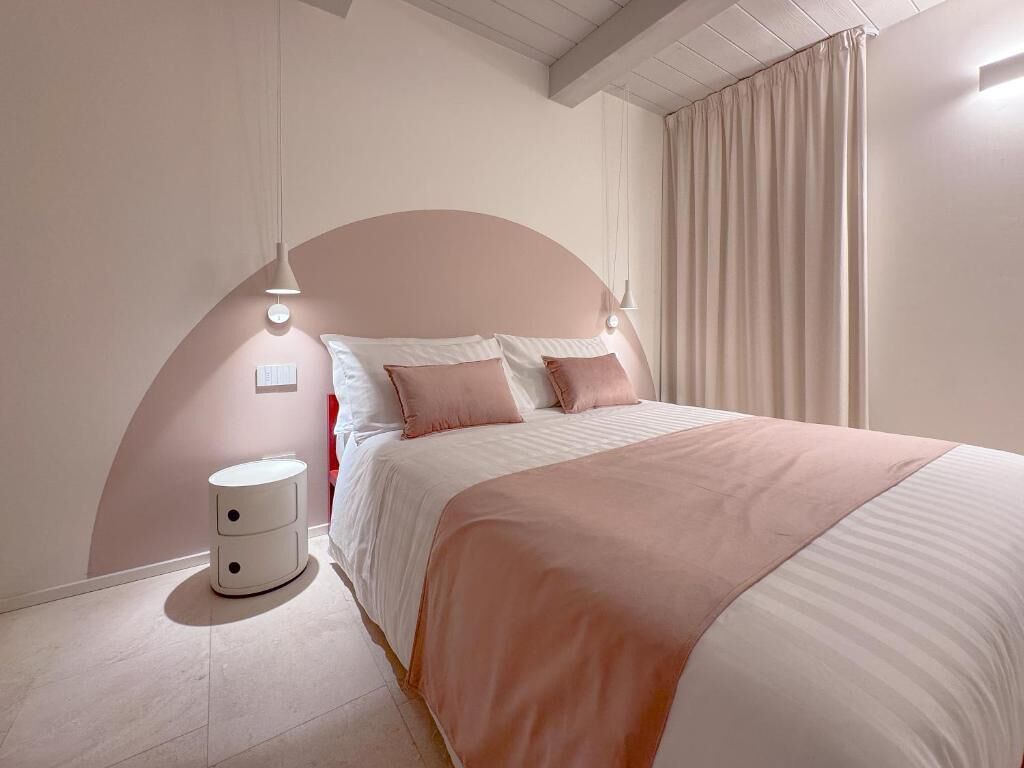Un dormitorio con cama, mesitas de noche y una lámpara fijada a la pared.
