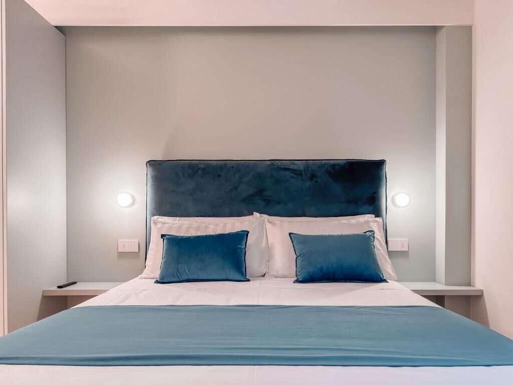 Un lit avec une tête de lit sombre, deux oreillers et une couvre-lit de couleur claire.