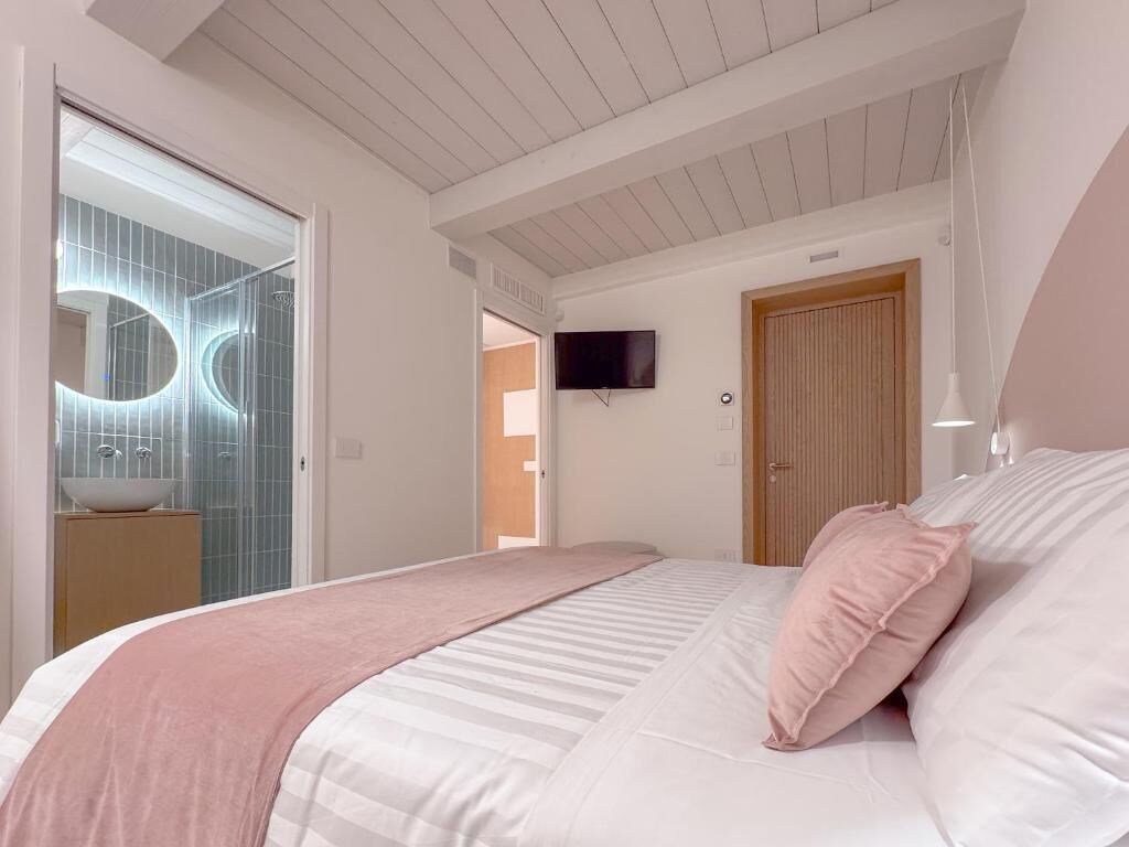 Un dormitorio con cama, televisión y baño de diseño moderno.