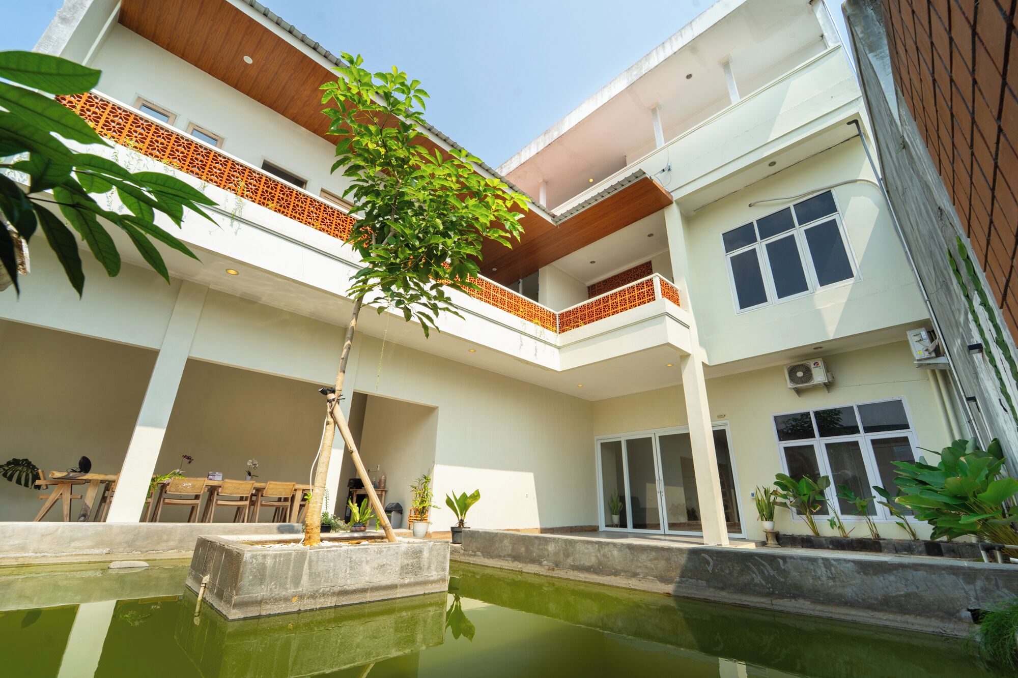 Um edifício com vários andares, um pátio, piscina e plantas em vasos.