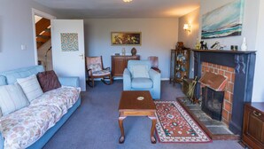 Ein Wohnzimmer mit einer Couch, Sesseln, einem Couchtisch, einem Kamin und einem Gemälde an der Wand.