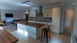 Una cocina moderna con una isla central, armarios blancos e iluminación colgante.