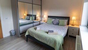 Un dormitorio con una cama grande, dos mesitas de noche, un espejo y un radiador.