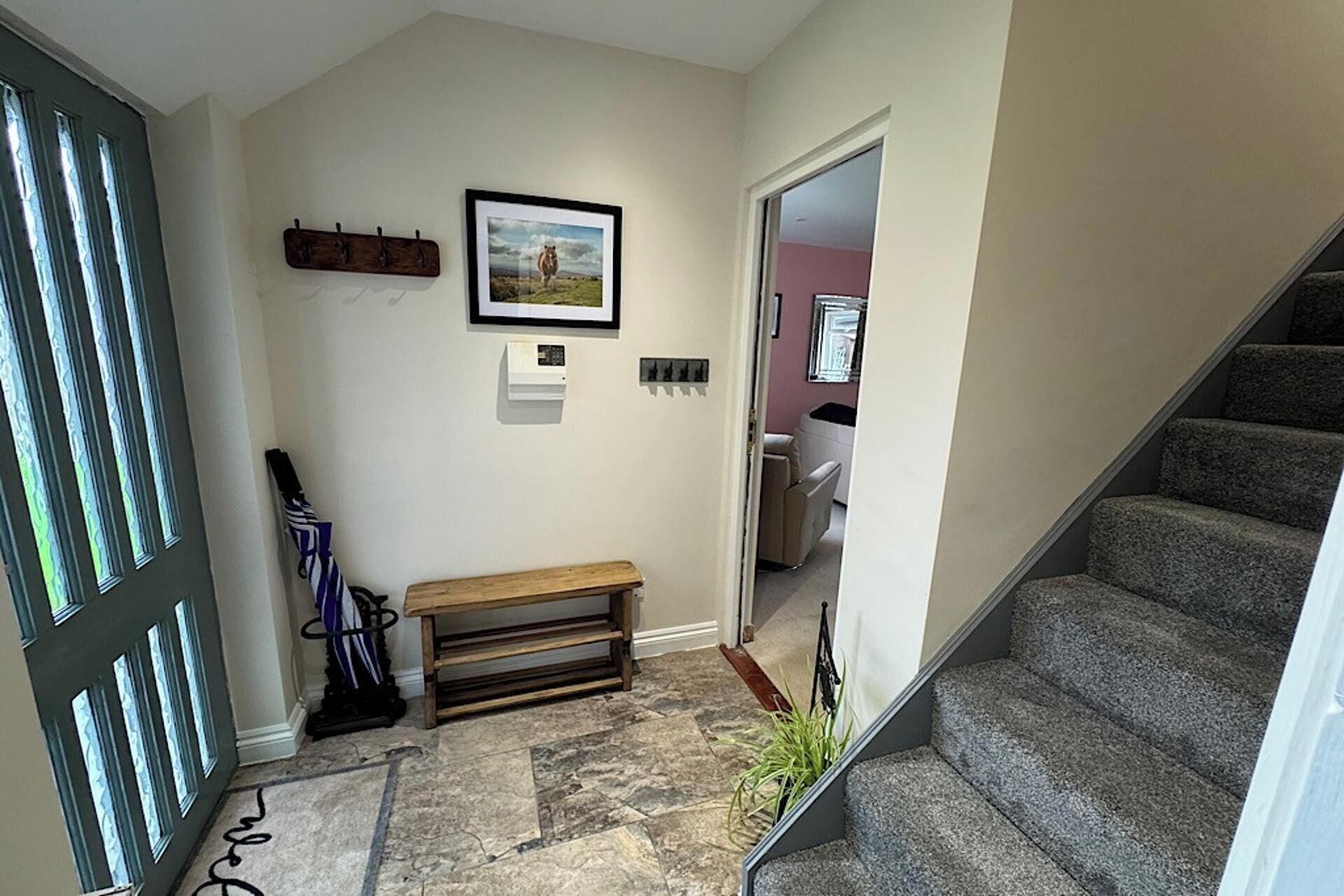 A hallway with a bench, a coat rack, a framed picture, and a staircase.