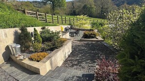 Jardín ajardinado con sendero de piedra, zona de estar y valla de madera.